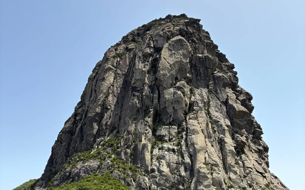 A tall tower of bare grey rock under a pale sky on La Gomera