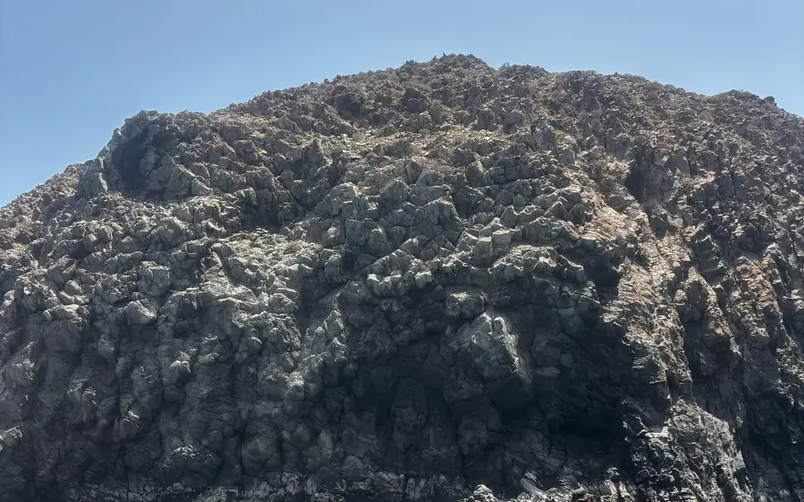 A dark, rugged lava cliff at the edge of the sea