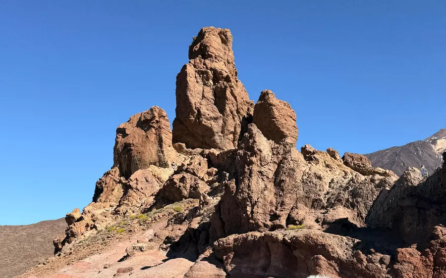 Tall red rock towers on a dry slope under a clear blue sky